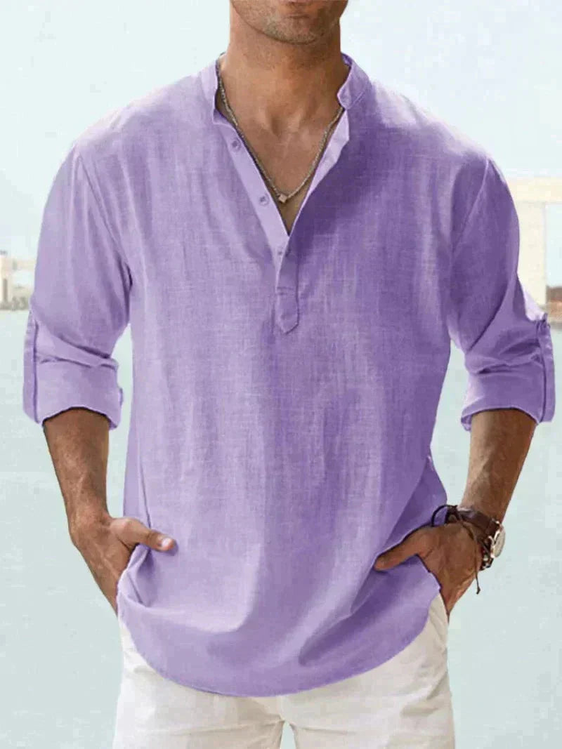 Camicia uomo lino viola, maniche lunghe arrotolate, stile casual estivo, collo alla coreana, abbinata a pantaloni bianchi.