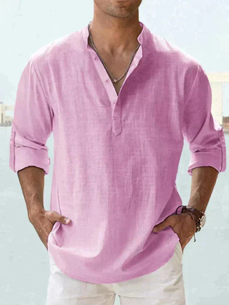 Camicia uomo in lino rosa, maniche lunghe arrotolate, stile casual elegante, abbinata a pantaloni bianchi. Moda estiva maschile.