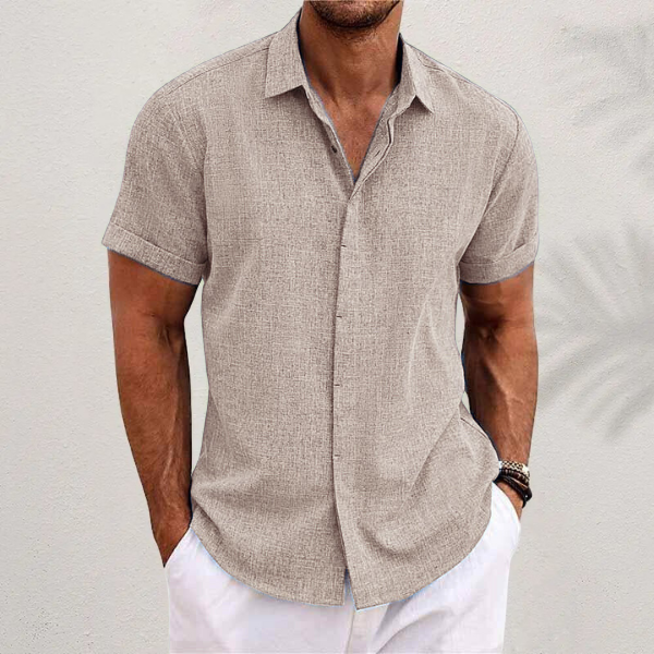 Camicia uomo lino beige a maniche corte, stile casual estivo, abbinata a pantaloni bianchi. Look fresco e moderno per la moda maschile.