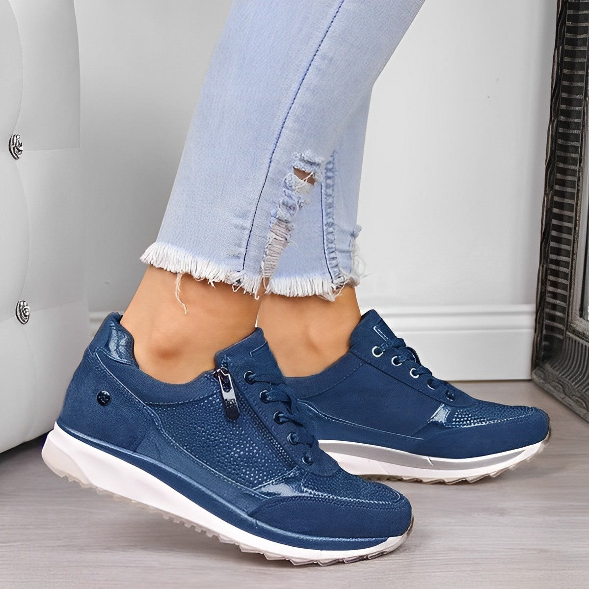 Jeans chiari strappati e sneakers blu da donna su pavimento in legno. Scarpe casual eleganti, moda femminile, calzature comode.