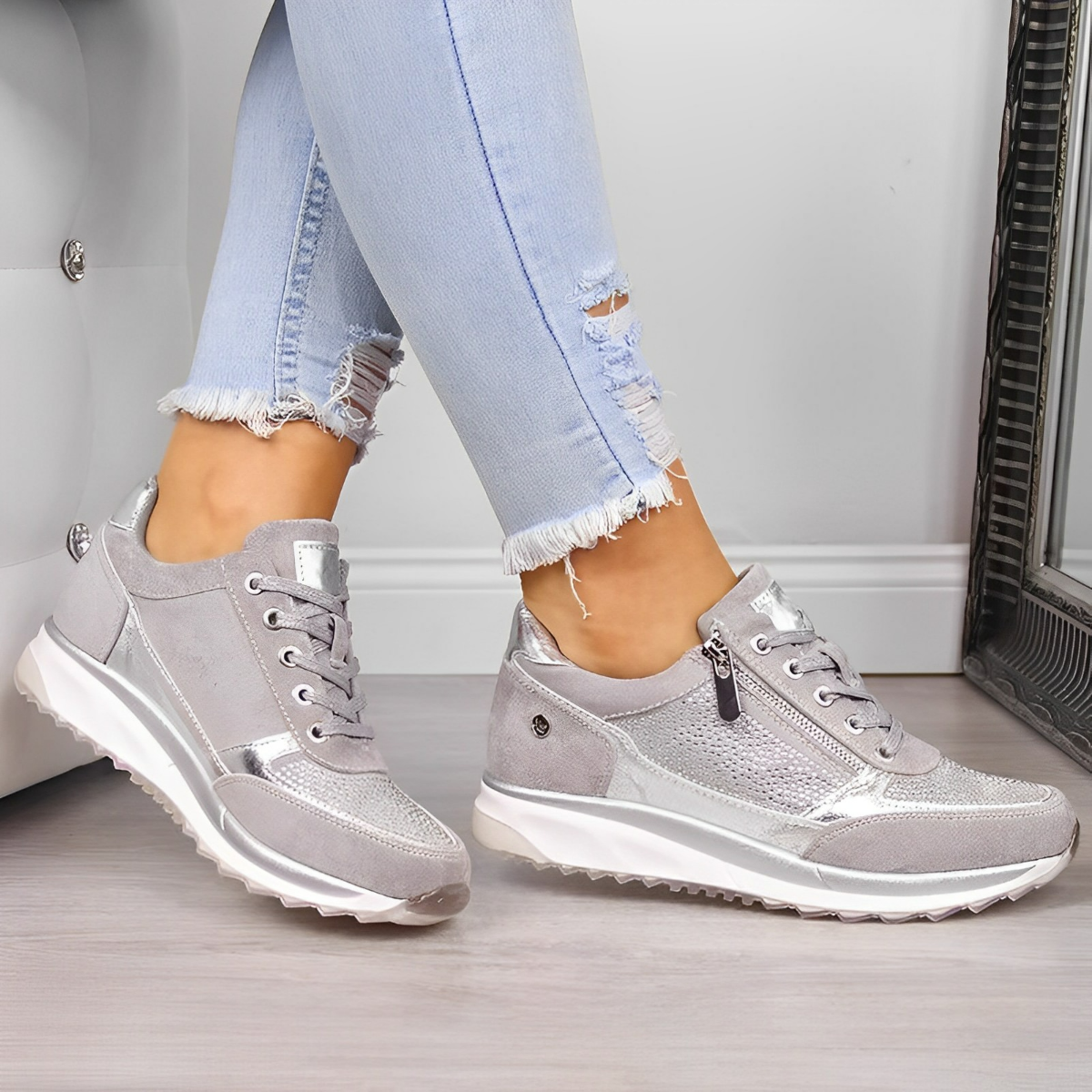 Scarpe da ginnastica grigie da donna, con dettagli in pelle scamosciata e cerniera, indossate con jeans chiari strappati. Moda casual e trendy.