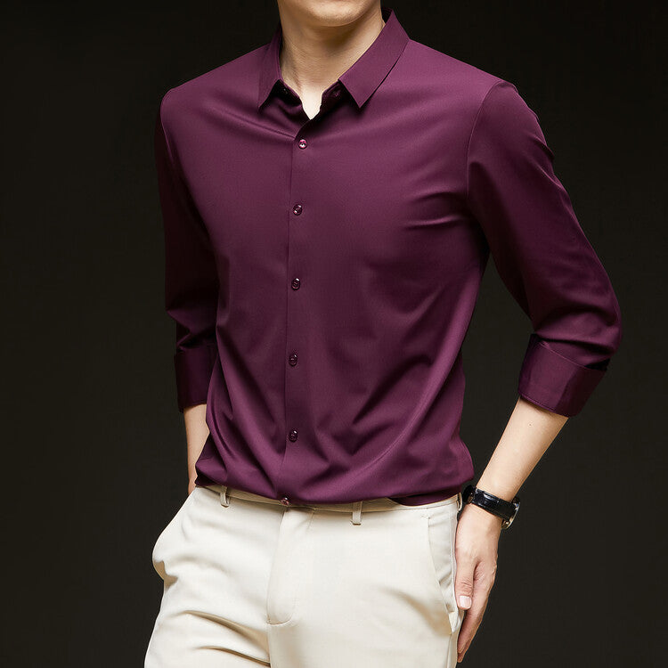 Camicia uomo elegante viola scuro, maniche lunghe, abbinata a pantaloni beige. Moda maschile, abbigliamento formale, stile sofisticato.