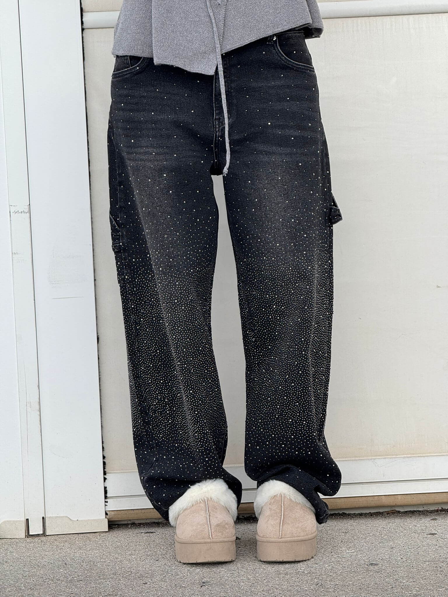 Jeans neri con dettagli glitterati, indossati con scarpe beige invernali. Moda casual, pantaloni decorati, stile urbano.