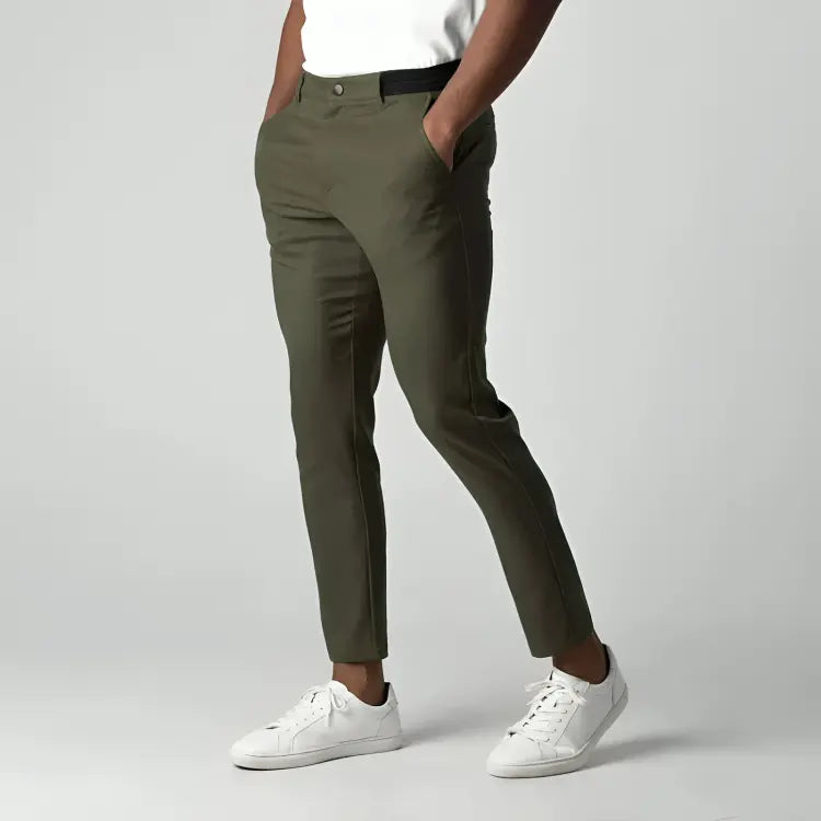 Pantaloni chino verde oliva da uomo, vestibilità slim, tasche laterali, abbinati a scarpe da ginnastica bianche, moda casual elegante.