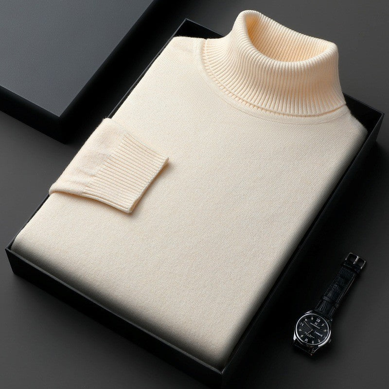 Maglione dolcevita beige in lana, confezionato in elegante scatola nera, accanto a orologio da polso nero su sfondo grigio scuro.