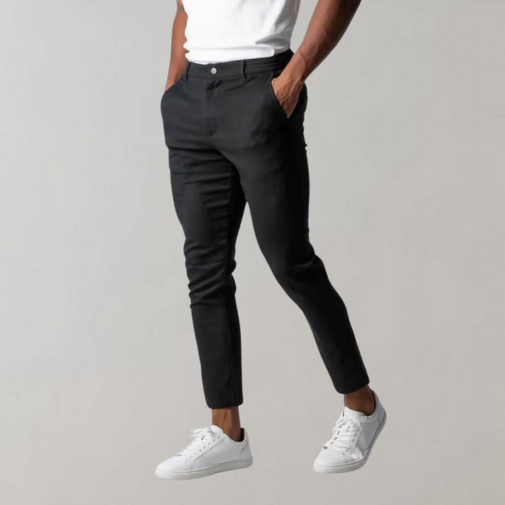 Pantaloni chino neri da uomo, eleganti e moderni, abbinati a scarpe da ginnastica bianche e maglietta bianca. Look casual e raffinato.