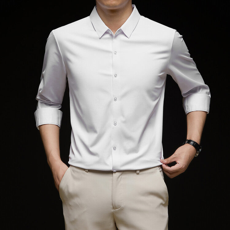 Camicia bianca elegante da uomo con maniche arrotolate, abbinata a pantaloni beige. Moda maschile, abbigliamento formale, stile contemporaneo.