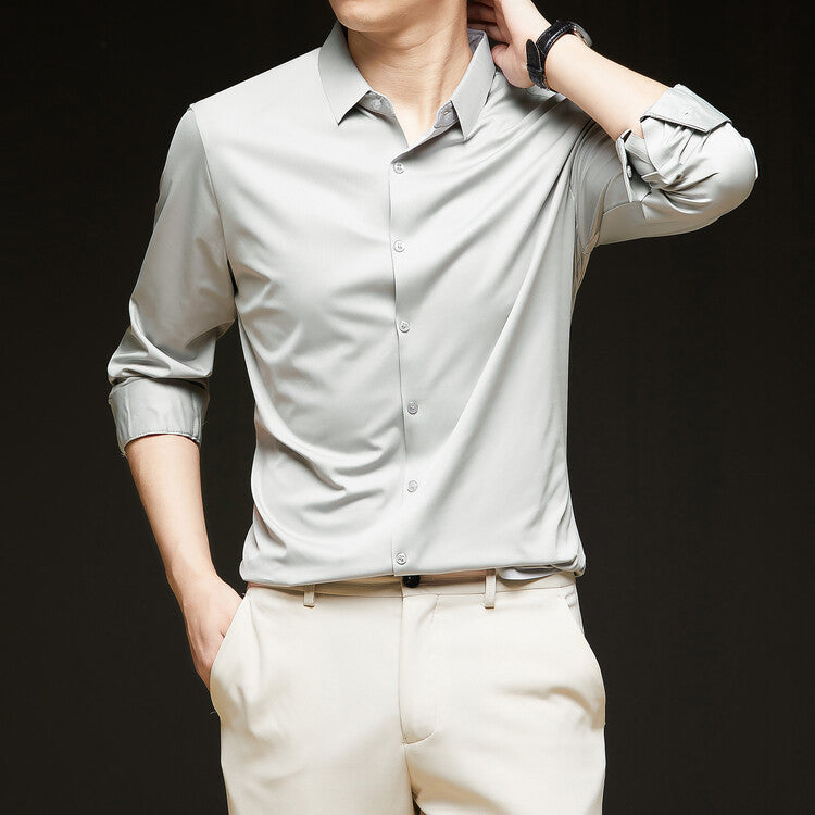 Camicia uomo elegante grigia, maniche lunghe arrotolate, abbinata a pantaloni chiari. Moda maschile, abbigliamento formale, stile moderno.