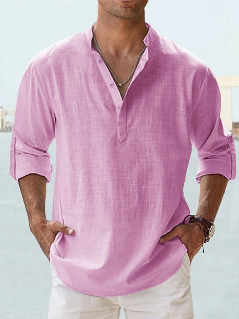 Camicia uomo lino rosa, maniche lunghe arrotolate, scollo a V con bottoni, stile casual estivo, indossata con pantaloni bianchi.