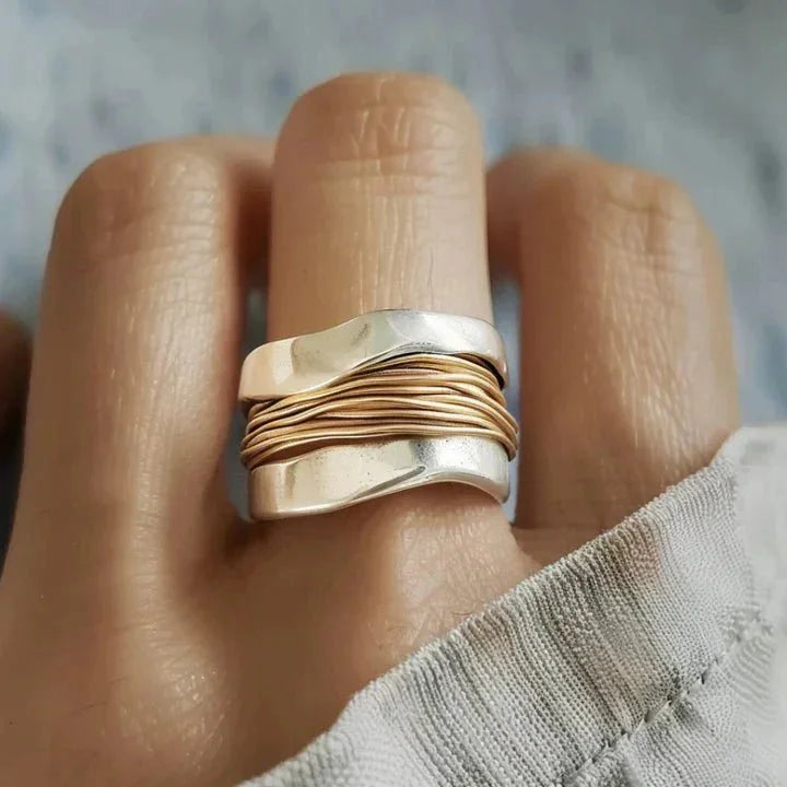 Dual-tone metal ring with wavy bands and wire-wrap detail.
