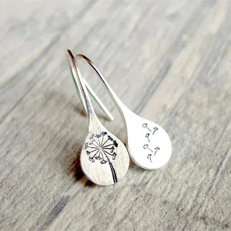 Sterling silver teardrop dangle earrings with dandelion motif, hook closure.