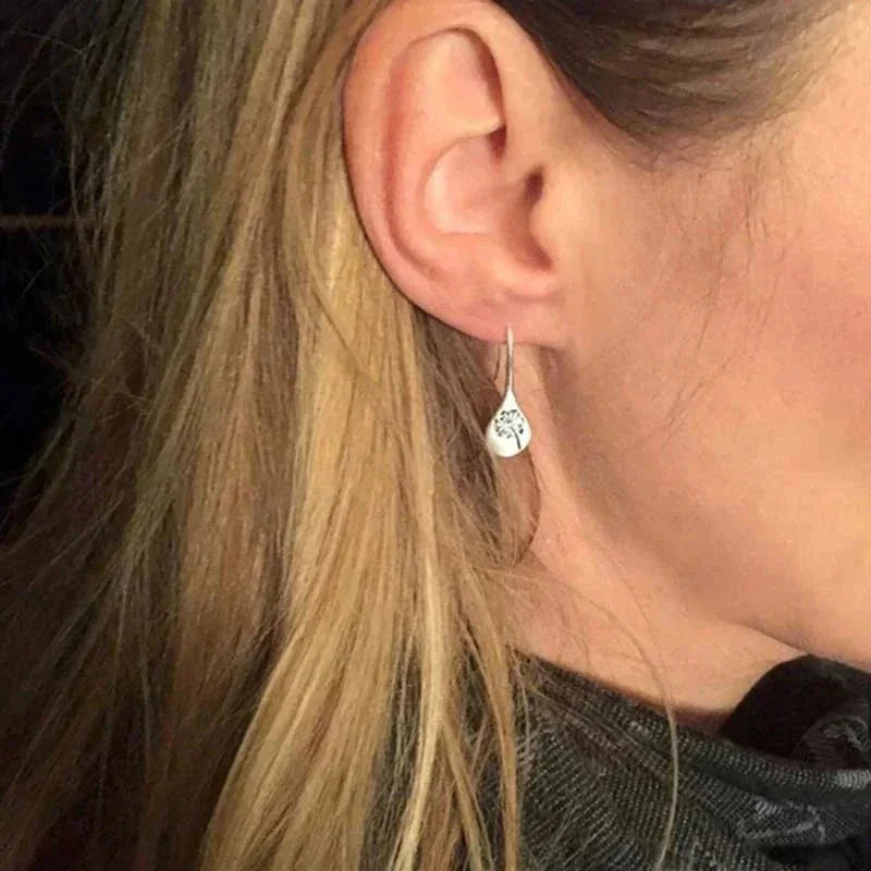 Sterling silver teardrop dangle earrings, each encasing a dandelion. Hook closure.