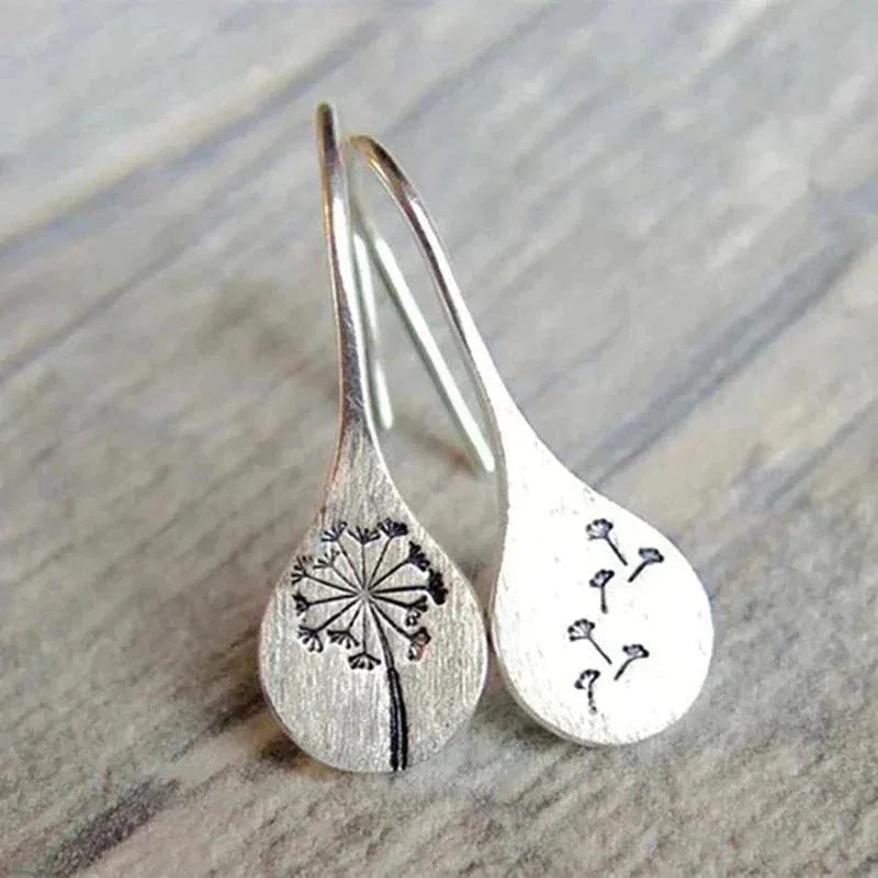 Sterling silver teardrop dangle earrings with dandelion design and hook closure.
